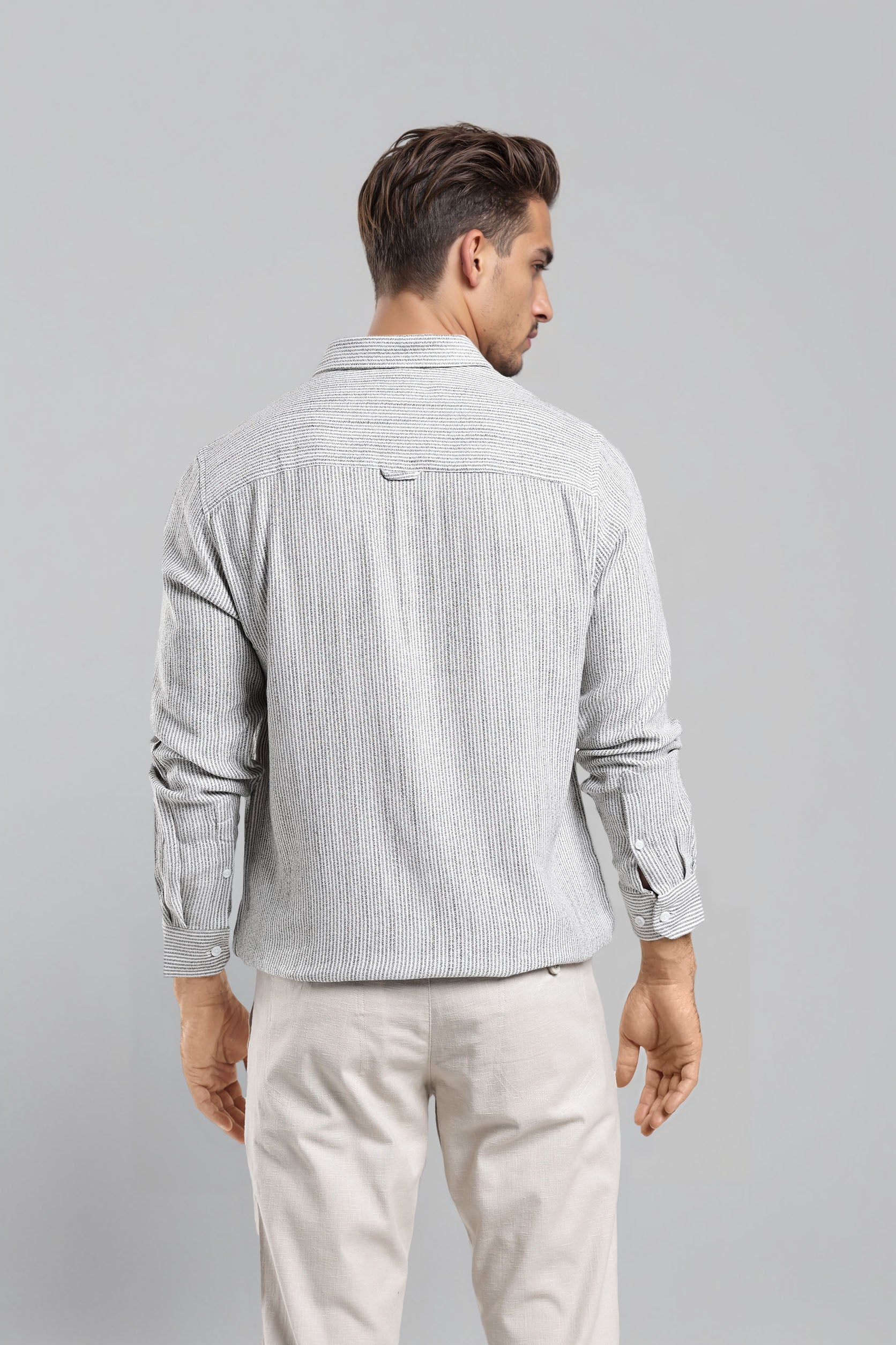 Man wearing a light gray textured shirt and beige pants on a gray background