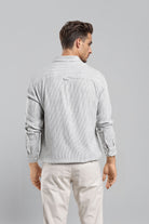 Man wearing a light gray textured shirt and beige pants on a gray background