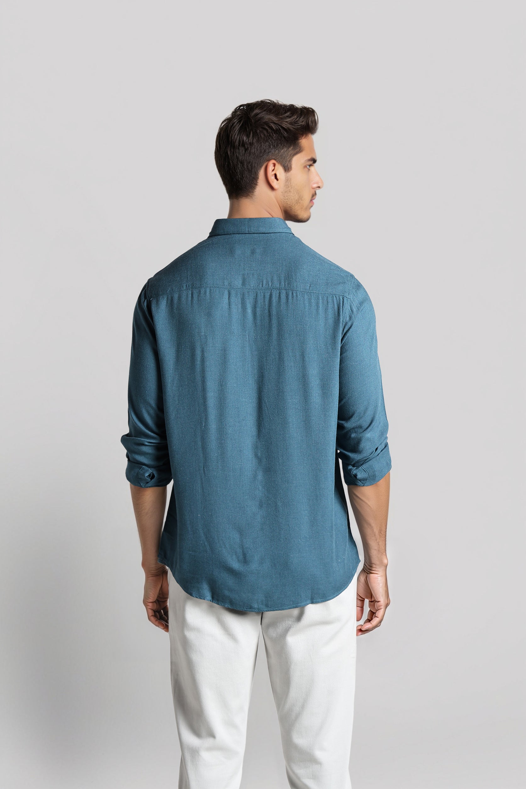 Man wearing a blue shirt and white pants on a light gray background