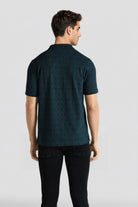 Man wearing a dark green patterned polo shirt on a white background