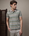Man wearing a green striped leaf clover green polo t shirt on a light gray background