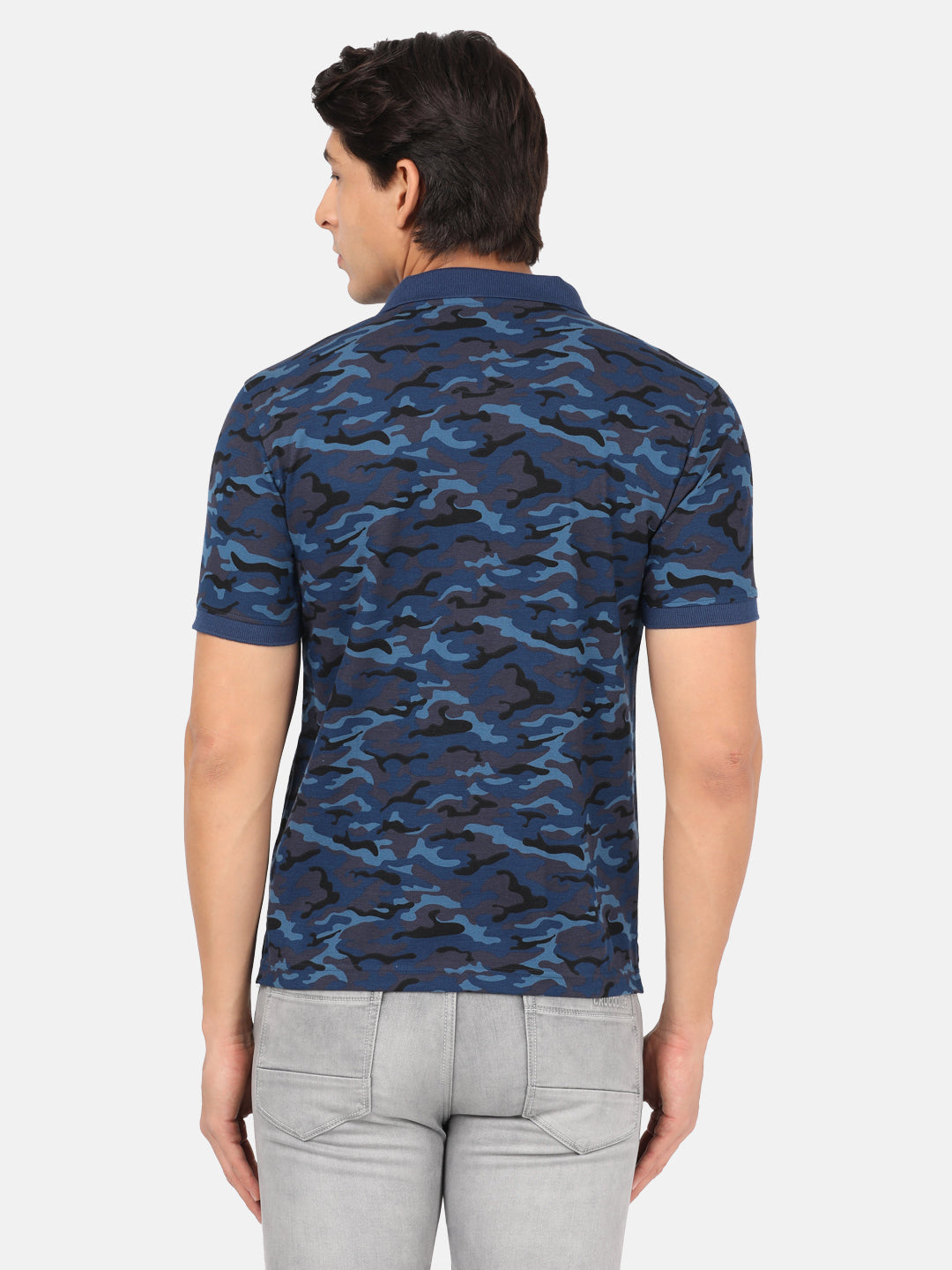 Man wearing a blue royal blue printed polo t shirt with casual styling on a gray background