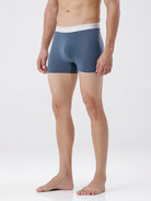 Man wearing a pair of blue boxer briefs on a white background