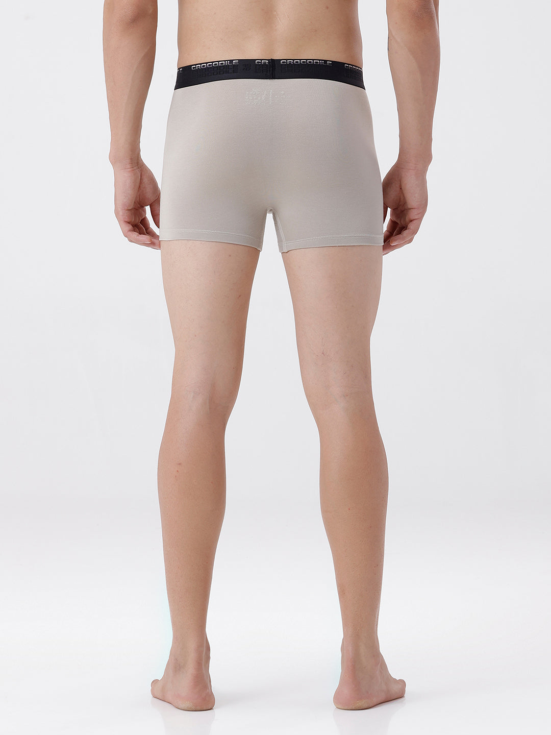 Person wearing beige boxer briefs with black waistband on a white background