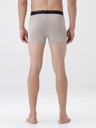 Person wearing beige boxer briefs with black waistband on a white background
