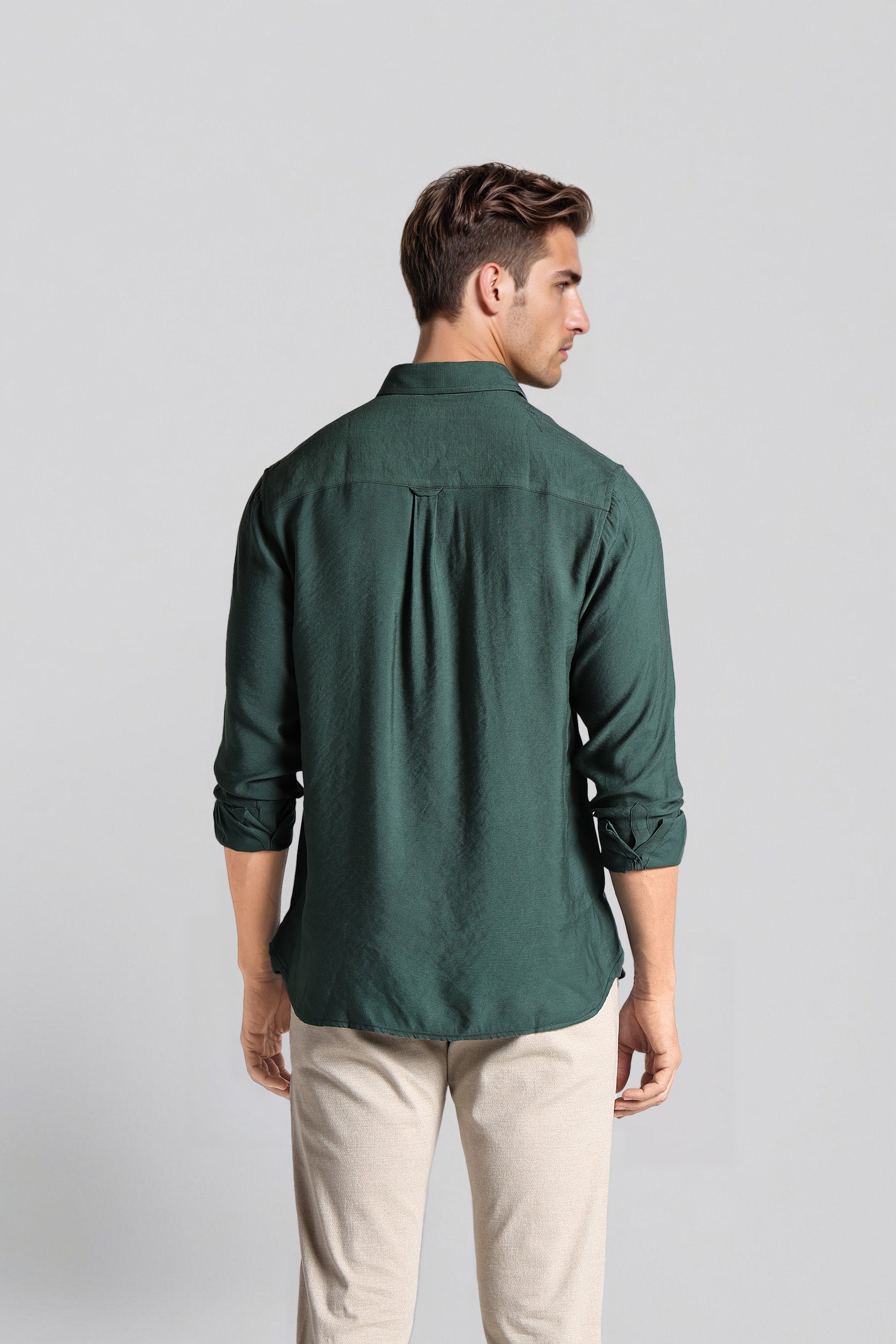 Man wearing a green shirt and beige pants against a light gray background