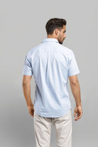 Man wearing a light blue polo shirt and beige pants on a gray background