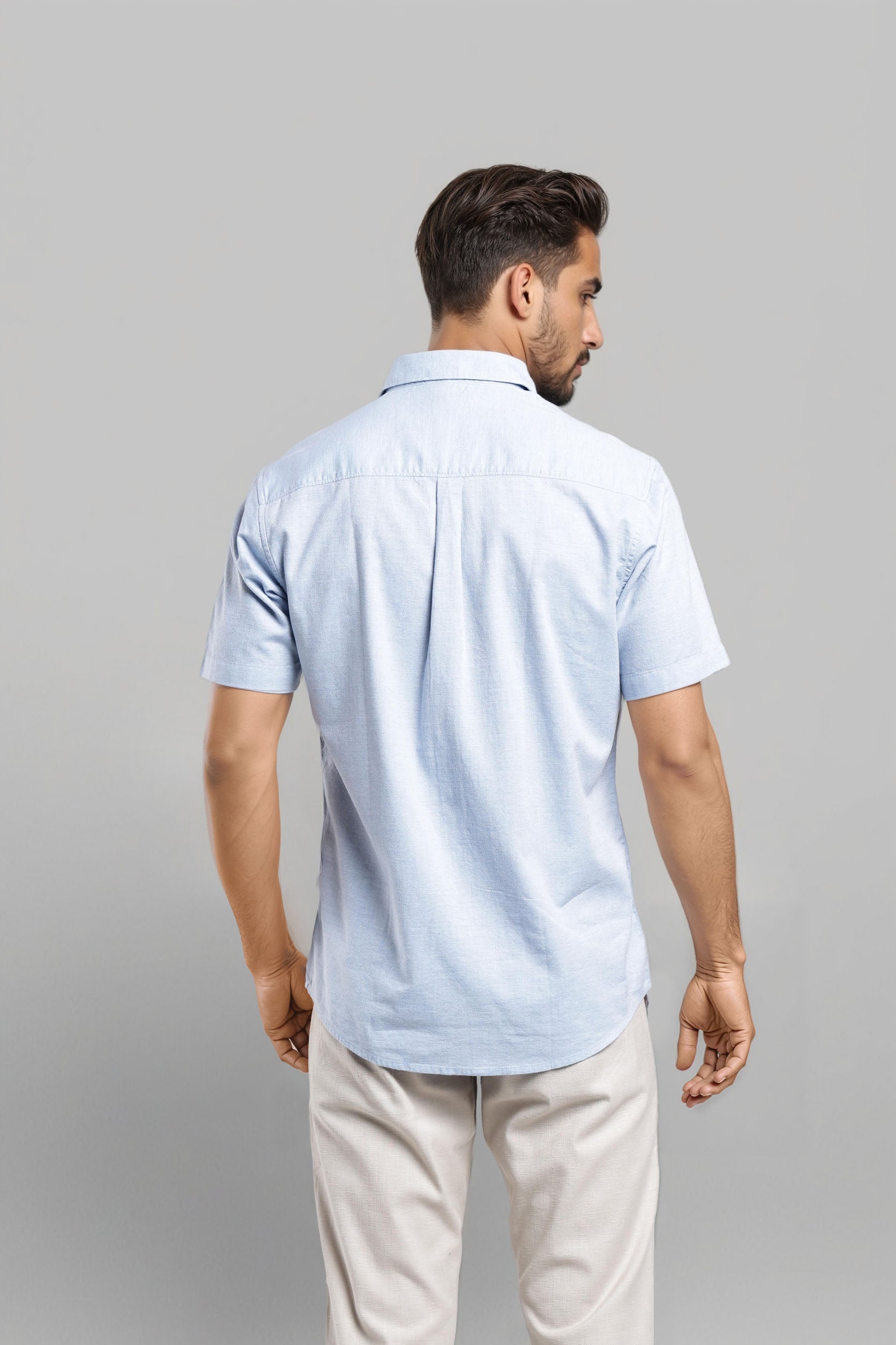 Man wearing a light blue polo shirt and beige pants on a gray background