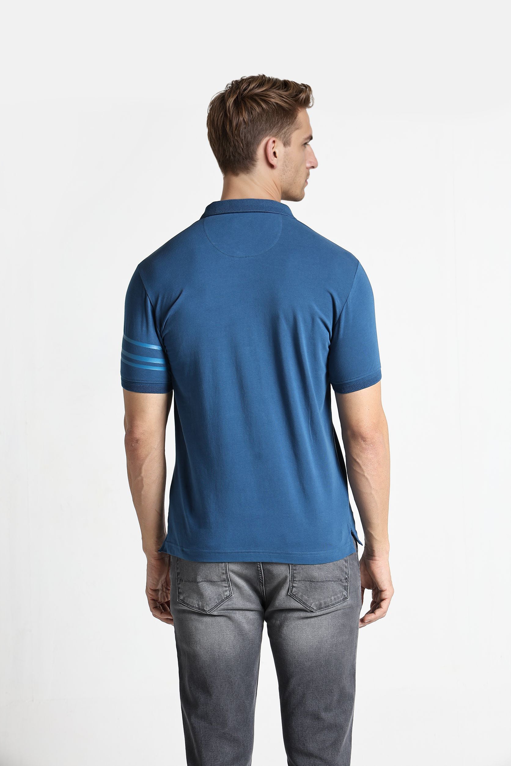 Man wearing a blue polo shirt and gray pants on a white background