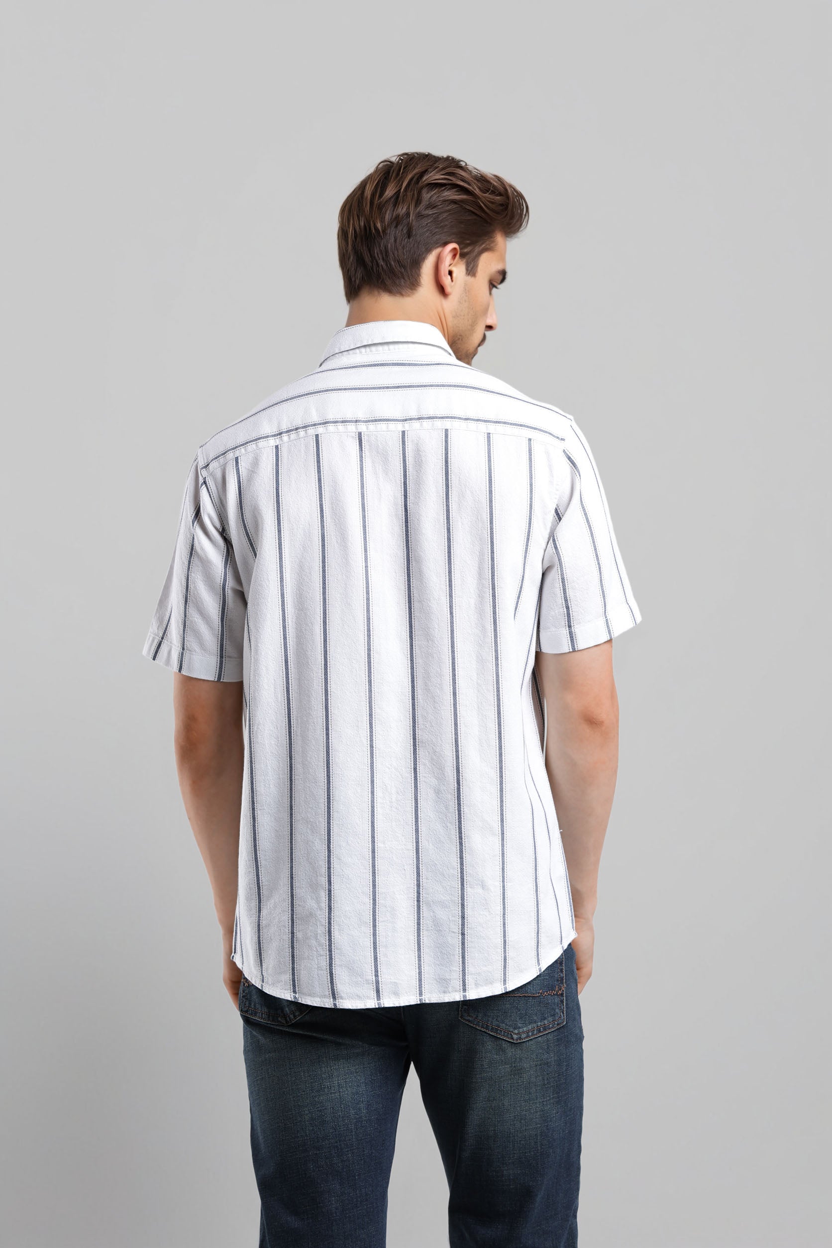 Man wearing a white short-sleeve shirt with black stripes on a gray background