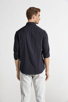 Man wearing a navy blue shirt and light gray pants on a white background