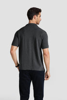 Man wearing a dark gray t-shirt and black pants on a light gray background