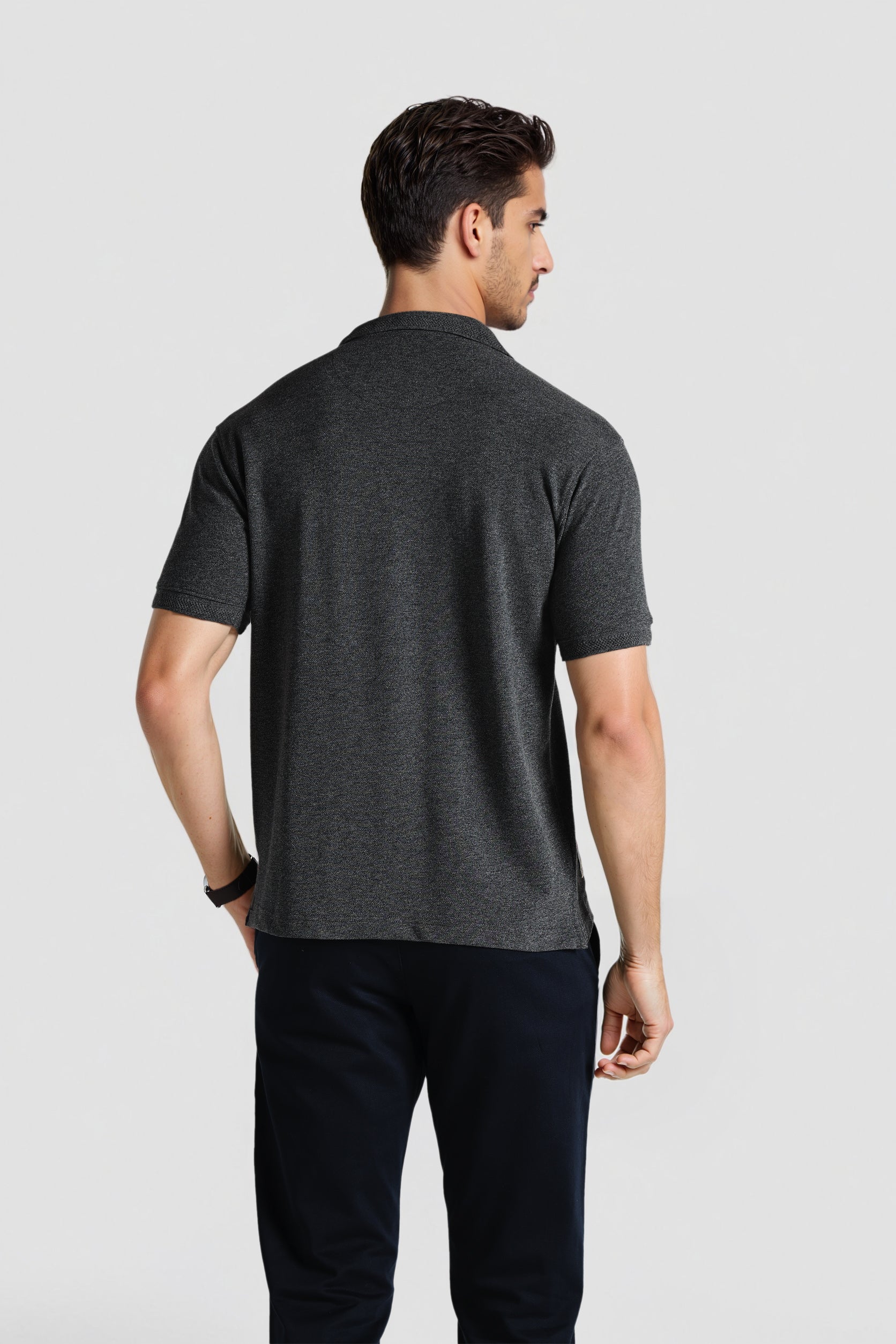 Man wearing a dark gray t-shirt and black pants on a light gray background