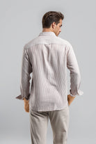 Man wearing a light gray striped shirt and pants on a plain background