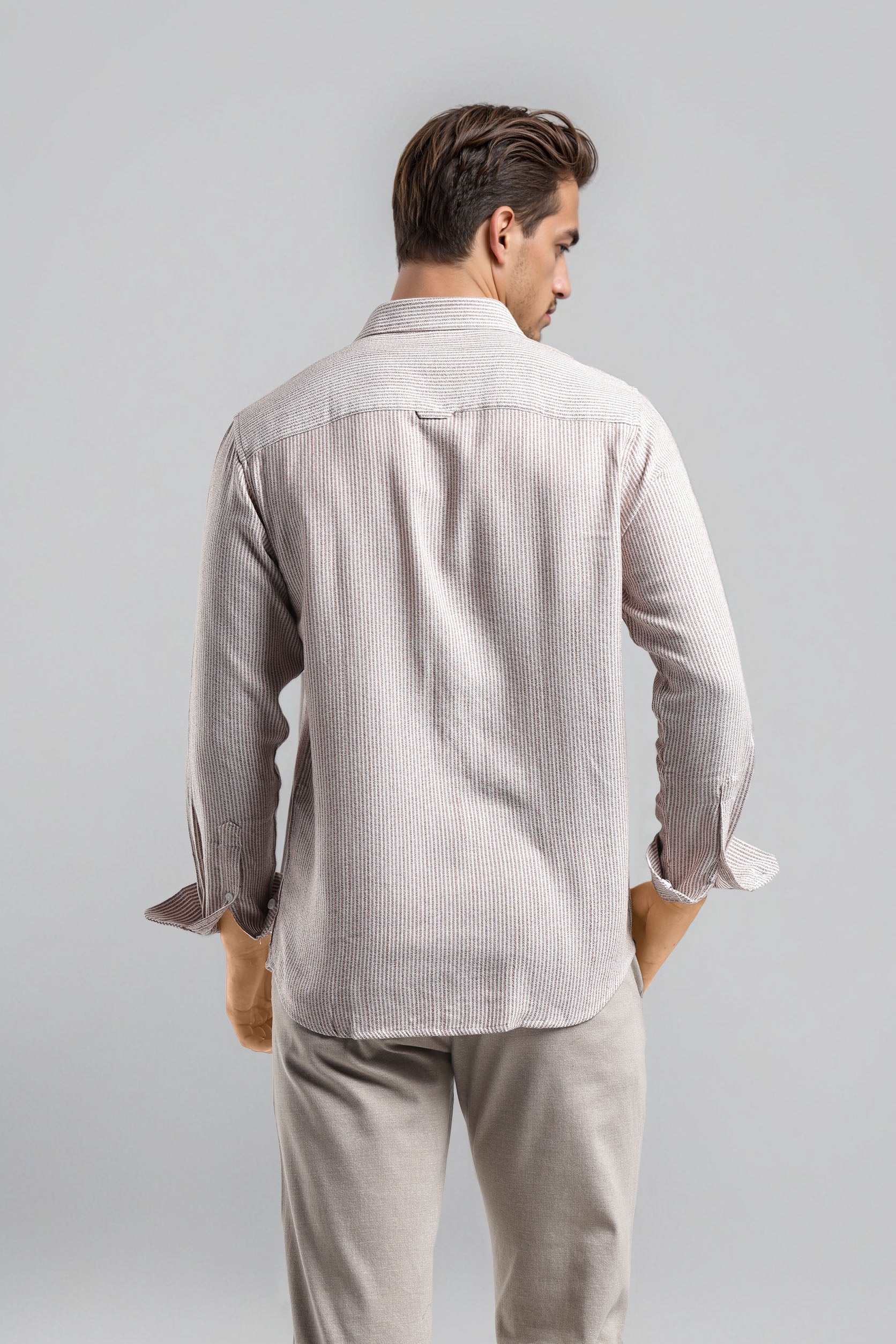 Man wearing a light gray striped shirt and pants on a plain background