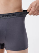 Person wearing gray boxer briefs with a visible brand logo on a plain background