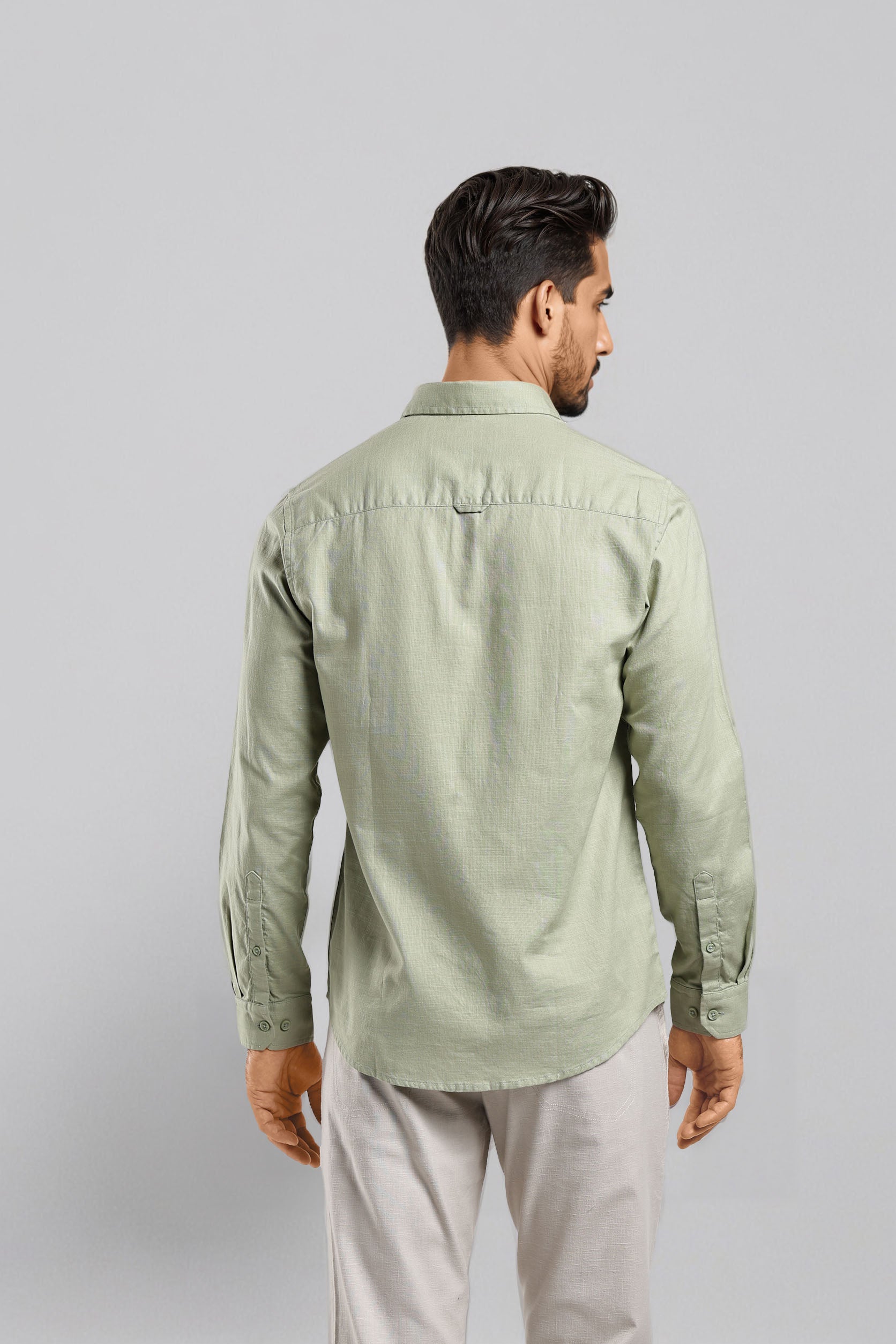 Man wearing a light green shirt and light gray pants on a plain background