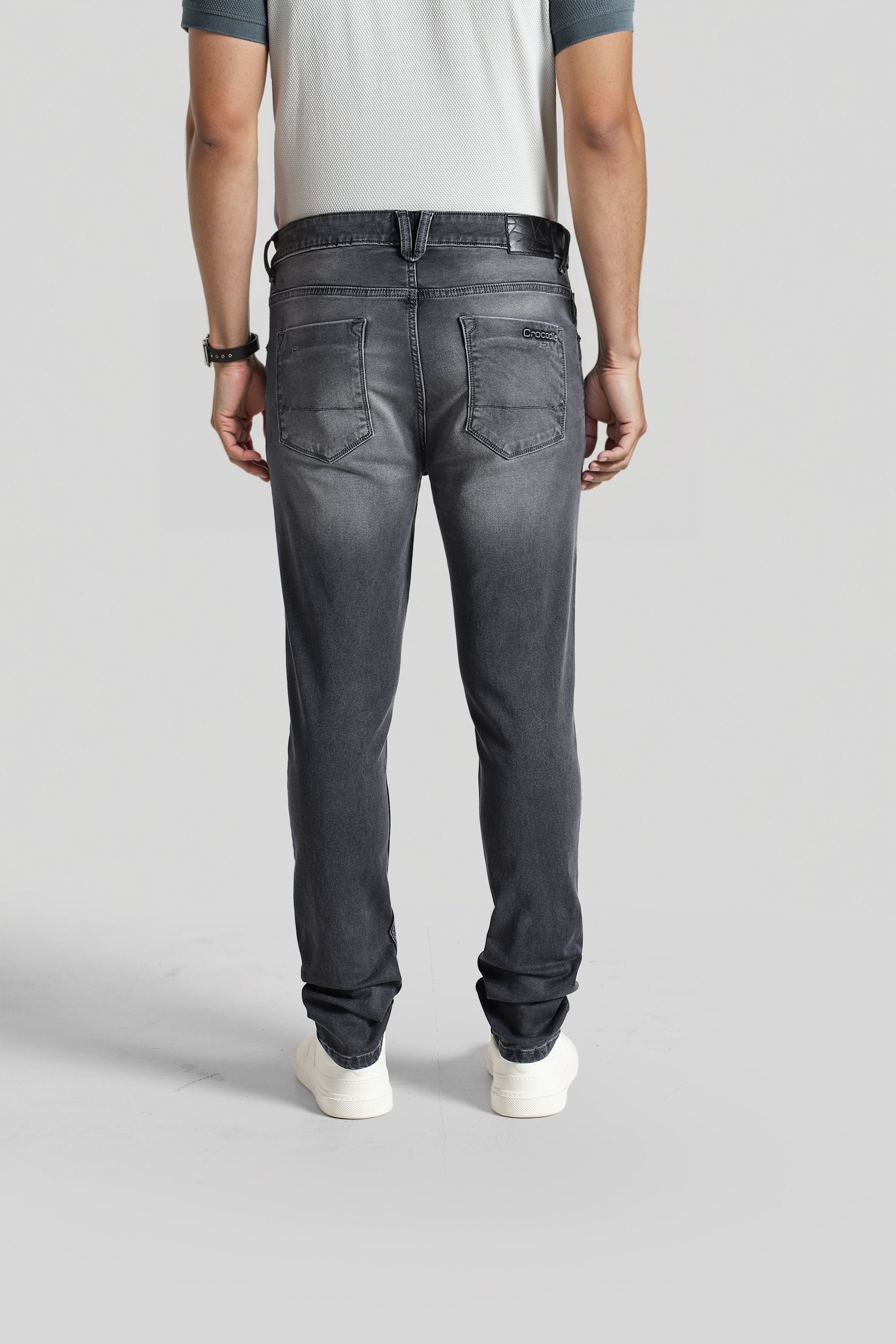 Person wearing black jeans on a plain background