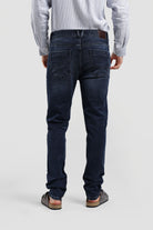 Person wearing dark blue jeans on a plain background