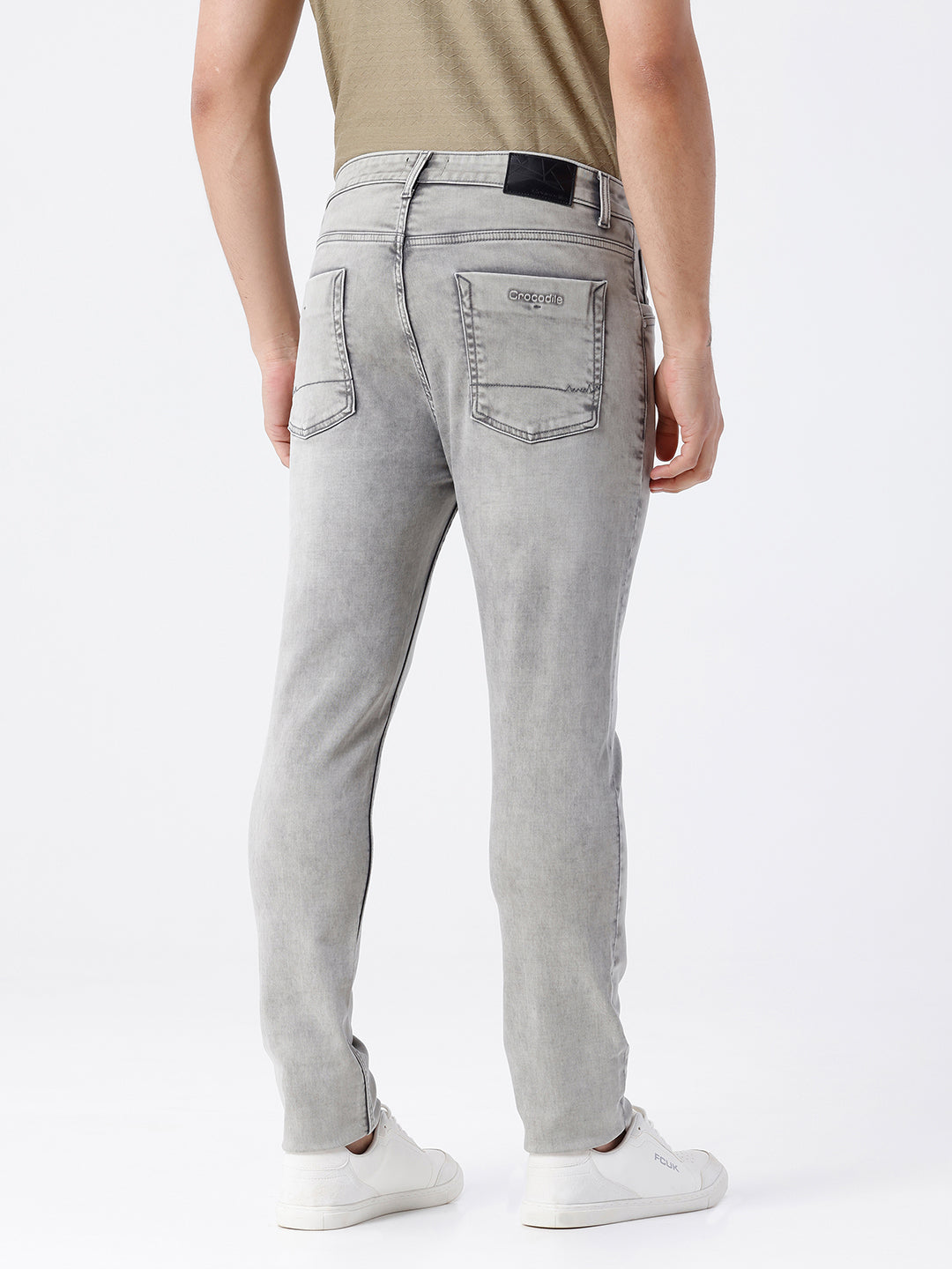 Man wearing a grey light grey knit slim fit jeans on a light gray background
