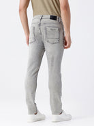 Man wearing a grey light grey knit slim fit jeans on a light gray background