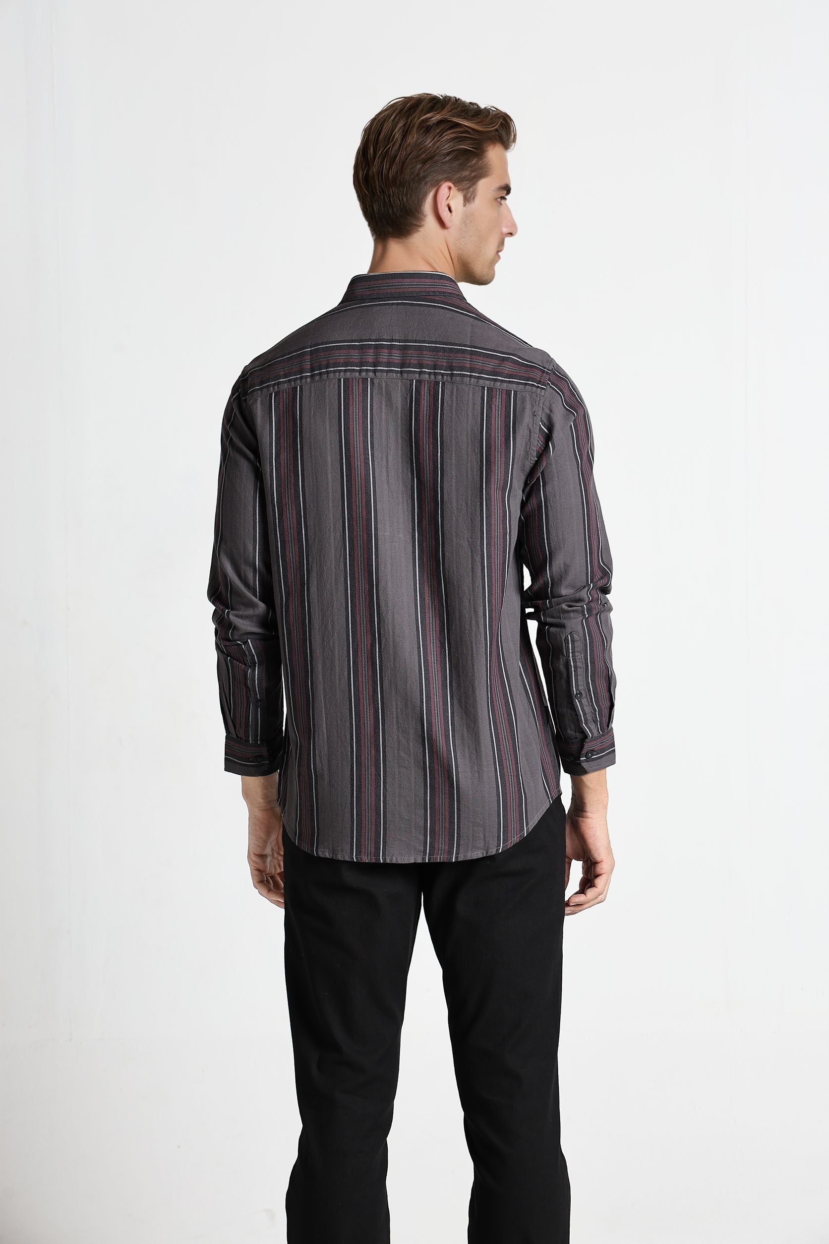 Man wearing a striped shirt and black pants on a white background