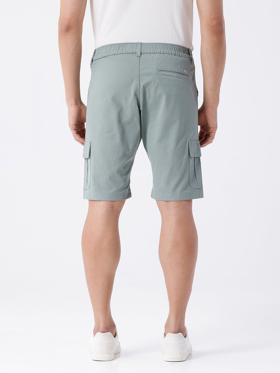 Man wearing a olive garment dyed cargo shorts in olive on a light gray background