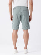 Man wearing a olive garment dyed cargo shorts in olive on a light gray background