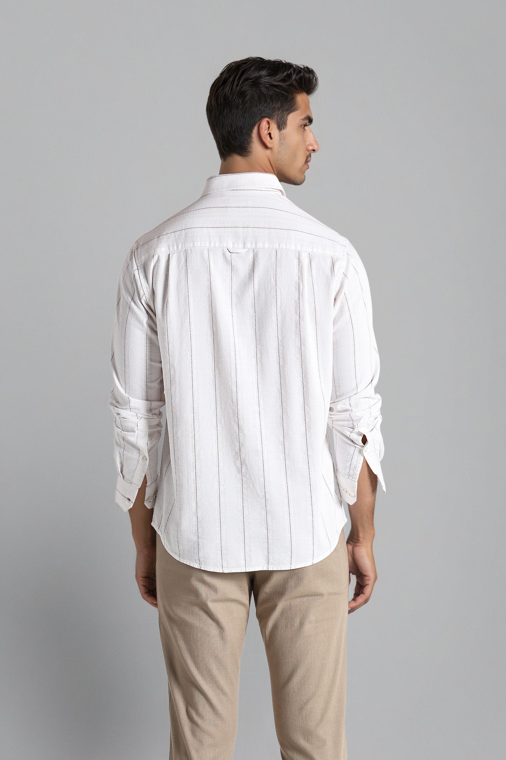 Man wearing a white striped shirt and beige pants against a gray background