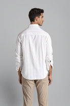 Man wearing a white striped shirt and beige pants against a gray background