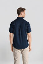 Man wearing a navy blue shirt and beige pants on a light gray background