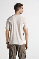 Man wearing a beige t-shirt and cargo pants on a white background