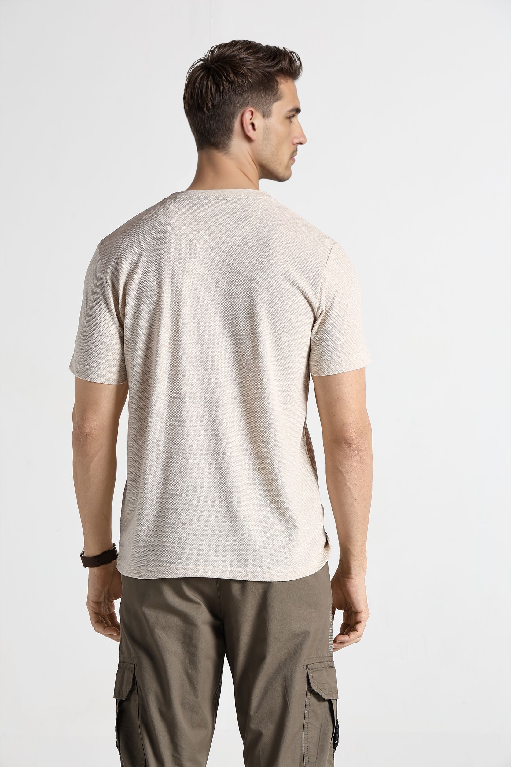 Man wearing a beige t-shirt and cargo pants on a white background