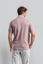 Man wearing a patterned pink polo shirt against a gray background