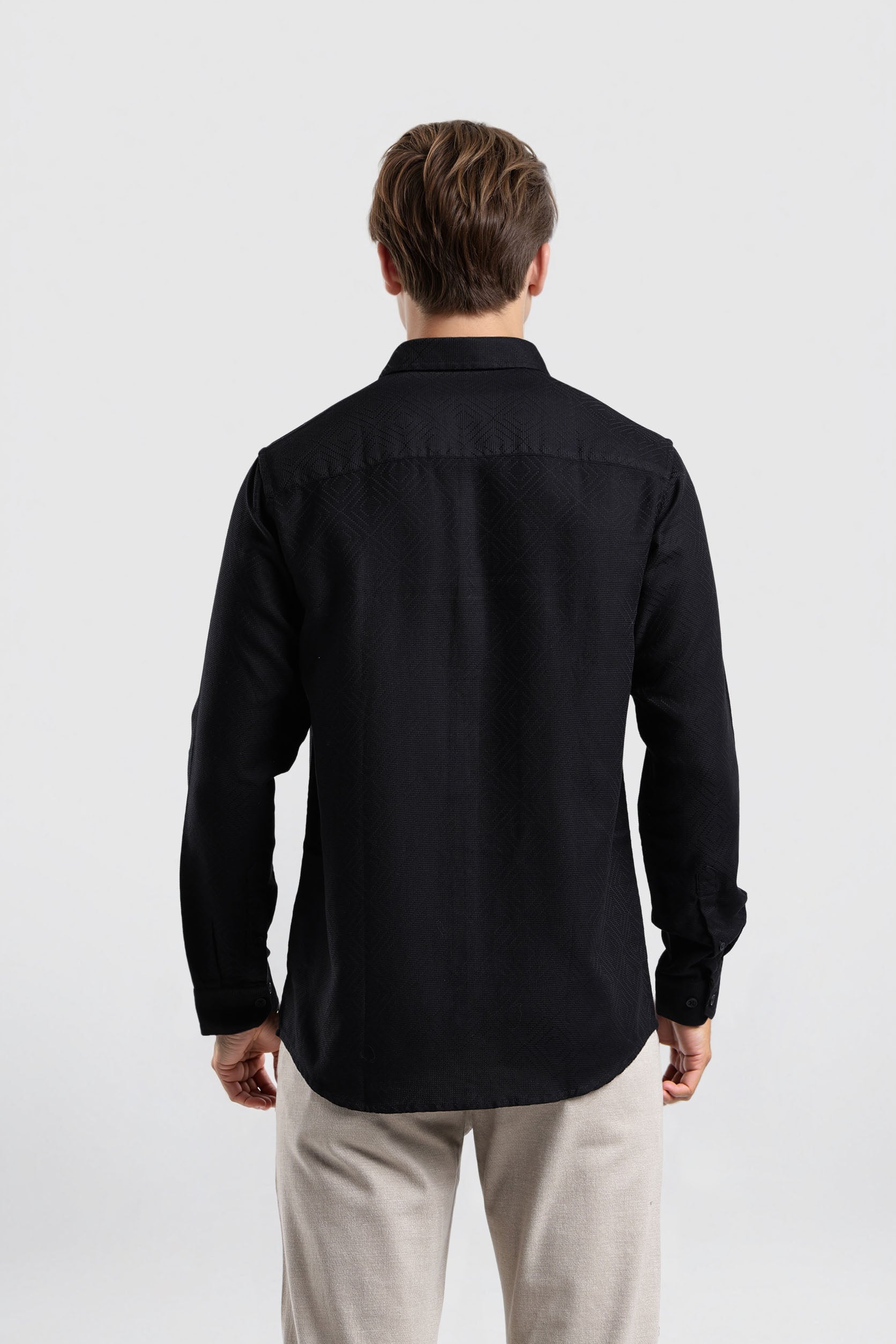 Man wearing a black shirt and light-colored pants on a white background