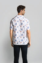 Man wearing a patterned shirt with short sleeves on a plain background