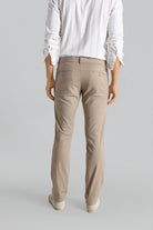 Person wearing beige pants and a white shirt on a gray background