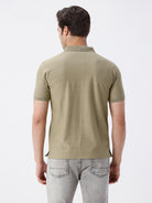 Man wearing a olive light olive structure comfort fit polo t shirt on a light gray background