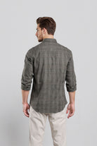 Man wearing a gray checkered shirt and white pants on a light gray background