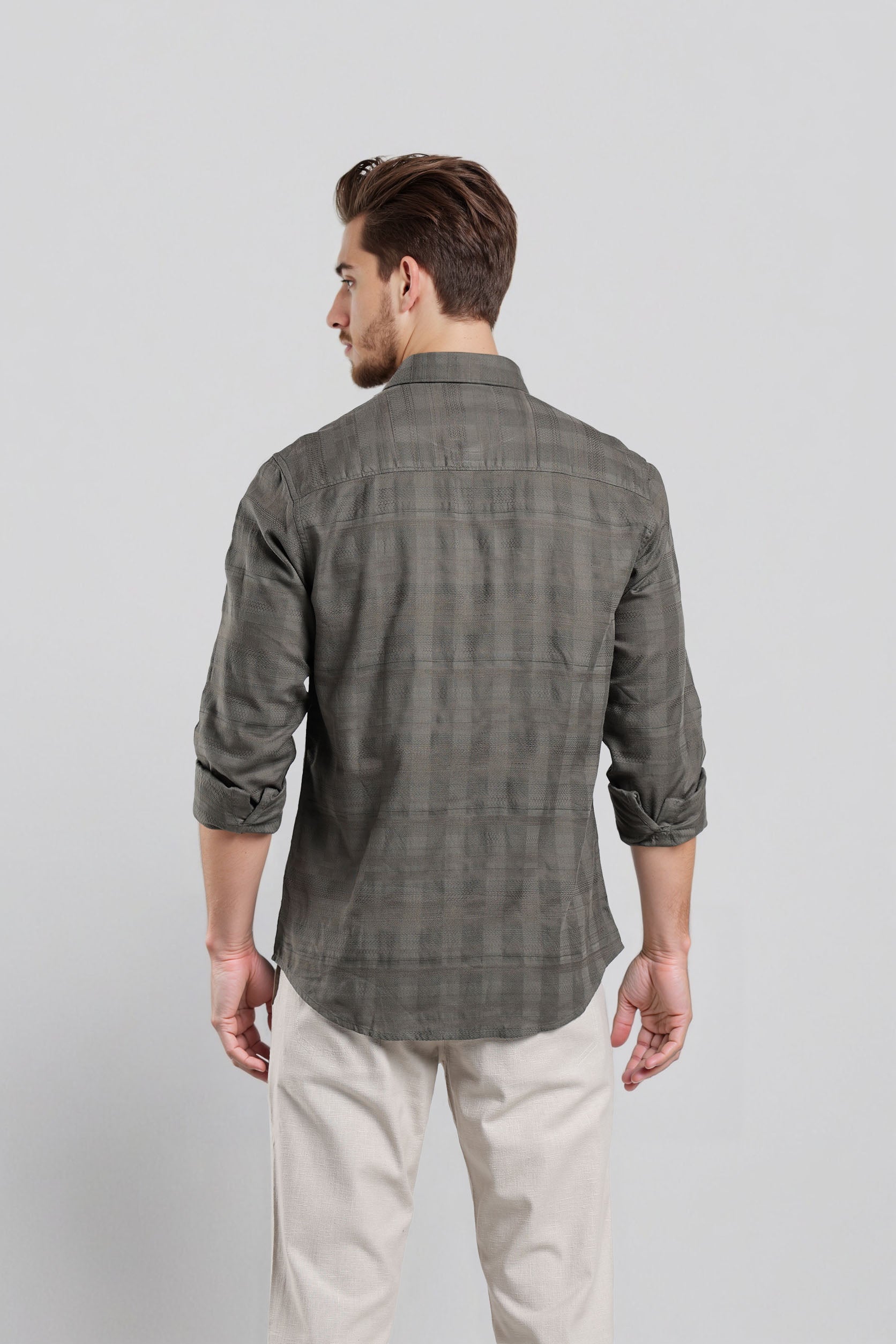 Man wearing a gray checkered shirt and white pants on a light gray background