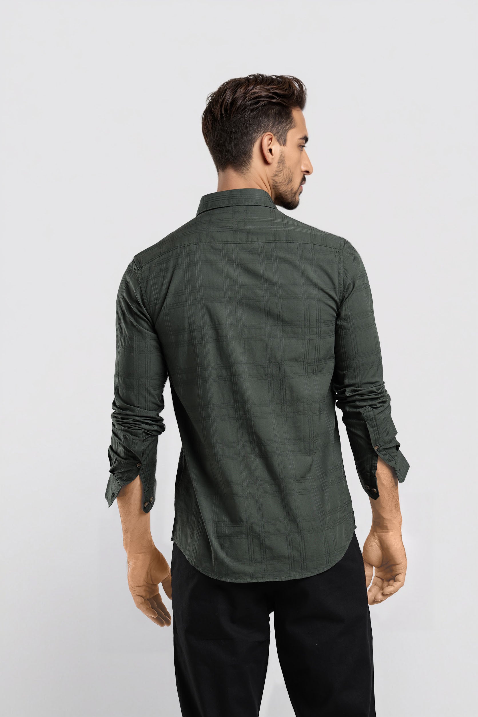 Man wearing a green shirt and black pants against a white background