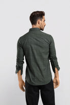 Man wearing a green shirt and black pants against a white background