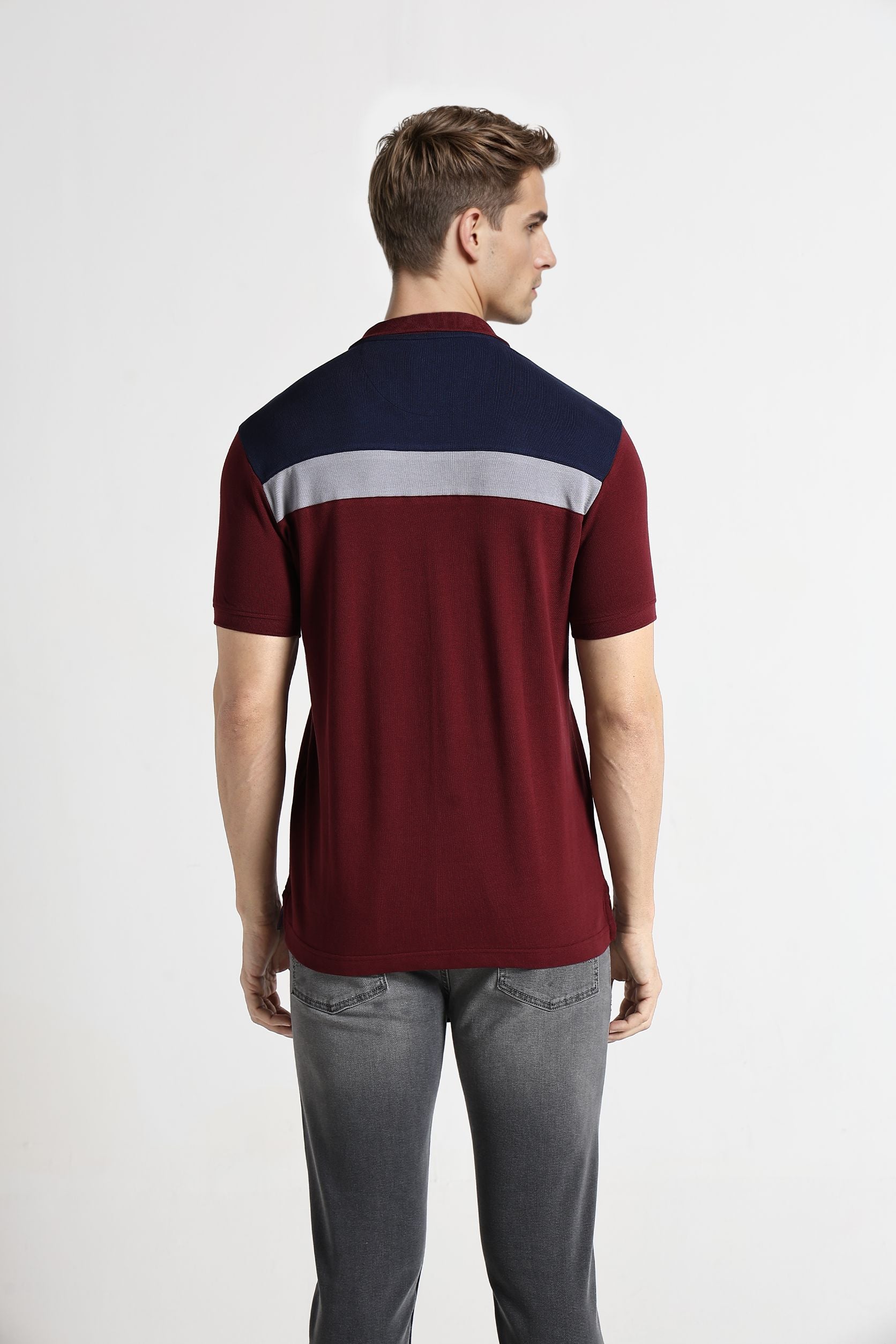 Man wearing a maroon and navy color-blocked shirt on a white background