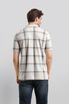 Man wearing a plaid shirt and jeans on a light gray background