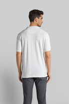 Man wearing a white t-shirt and gray pants on a light gray background