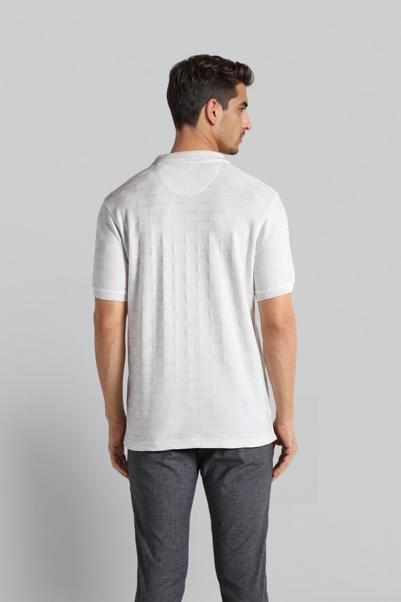 Man wearing a white t-shirt and gray pants on a light gray background