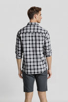 Man wearing a black and white checkered shirt and gray shorts on a light gray background