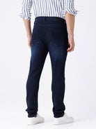 Man wearing a blue dark blue knit slim fit jeans with casual styling on a gray background