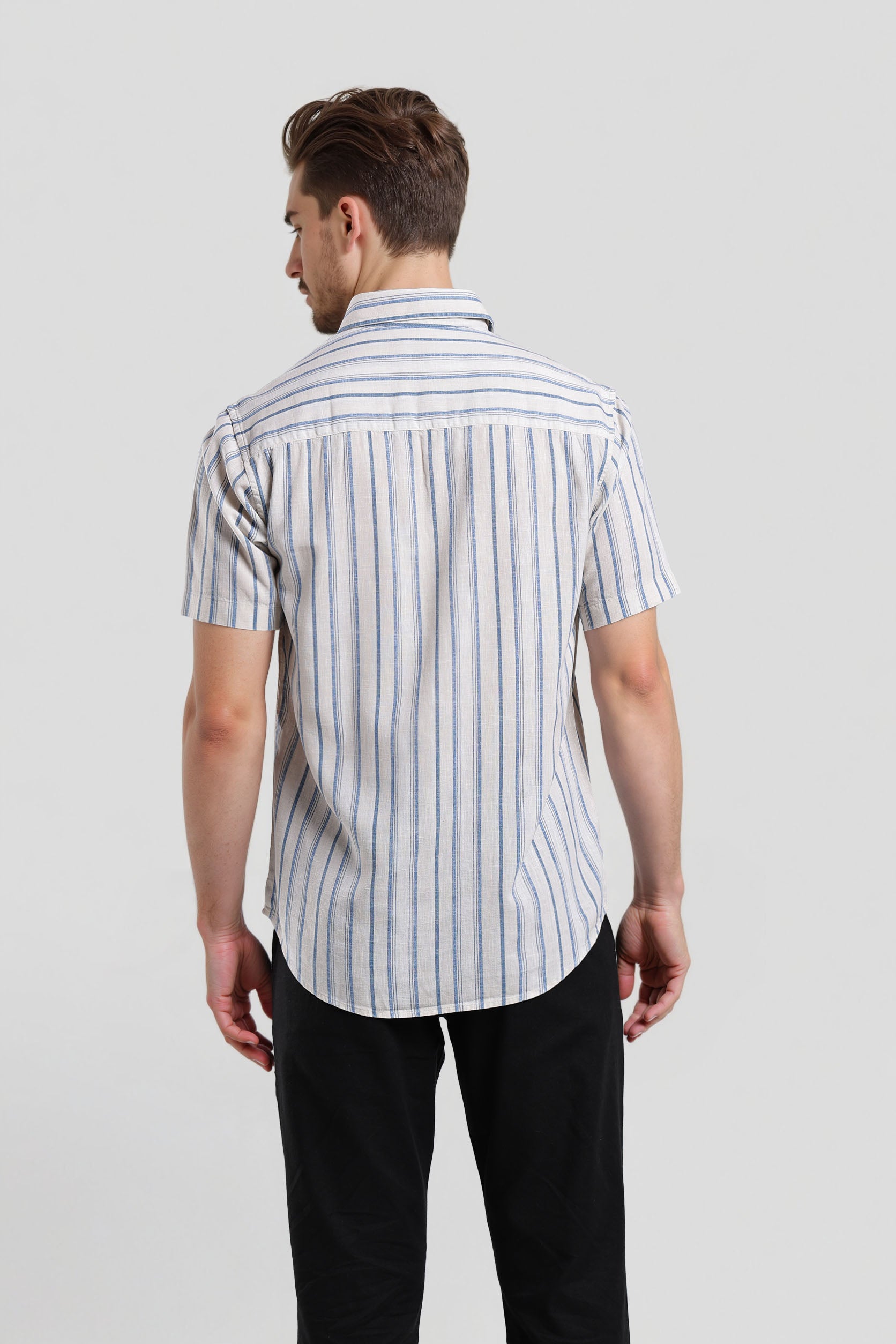 Man wearing a striped shirt and black pants on a light gray background