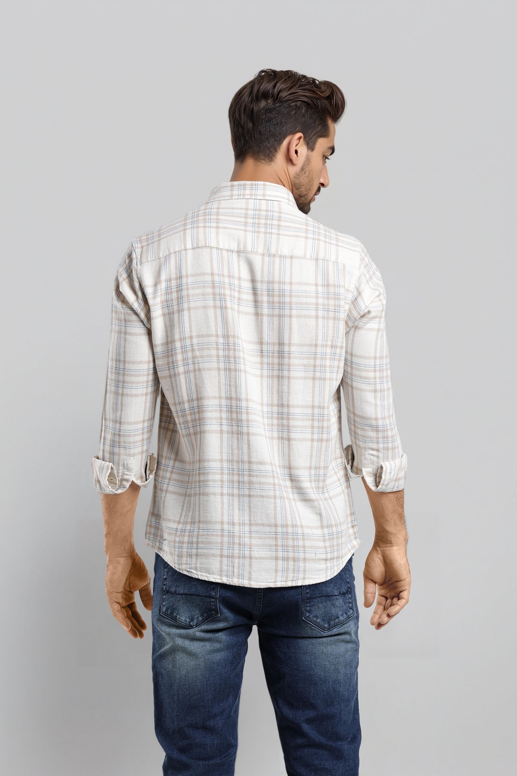 Man wearing a white checkered shirt and blue jeans on a gray background